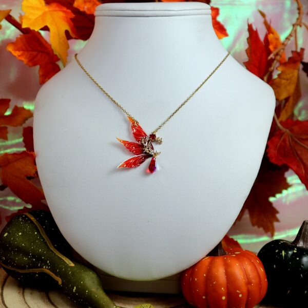 collier assymétrique avec un quartier de lune serti de pierres rouges et blanches, avec 3 ailes de fées en dégradé de rouge et un cristal de Swarovski